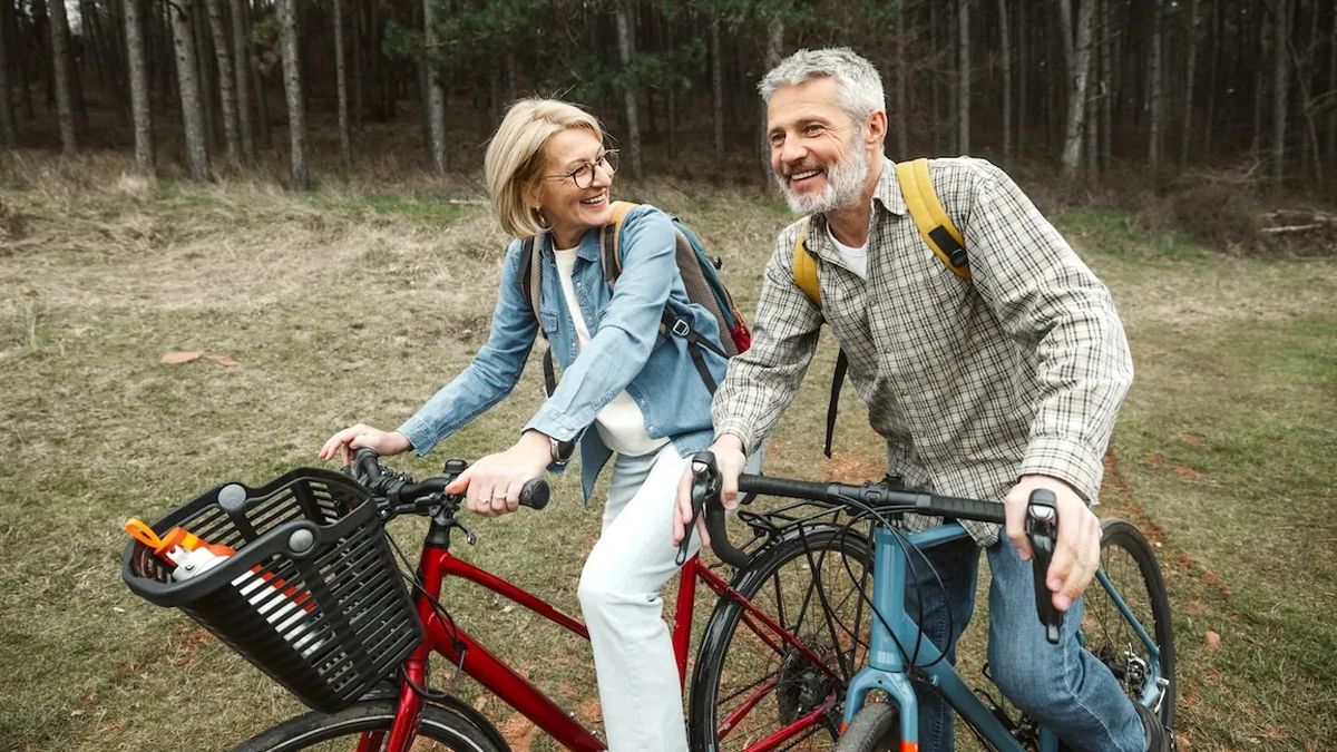 Ενεργό ζευγάρι 50+ κάνει ποδήλατο στη φύση, εικόνα Active Aging και Longevity Economy